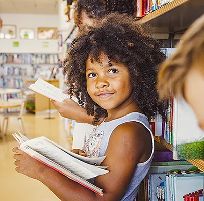 A child holding books in a library